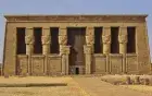 Approaching Dendera by Nile — the temple pylon visible as the lotus boat arrives by water